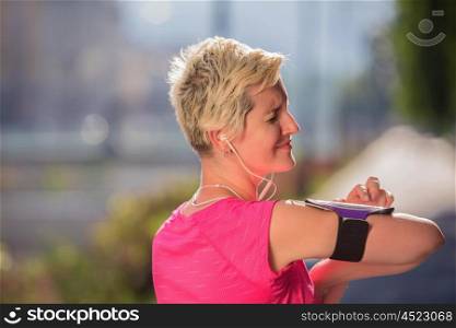 jogging woman setting music and running route on smart phone putting earphones before morning run