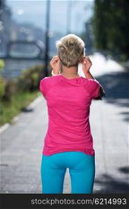 jogging woman setting music and running route on smart phone putting earphones before morning run