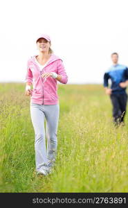 Jogging young fit couple running field meadow in sportswear tracksuit