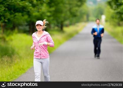 Jogging young fit couple running park road in sportswear tracksuit