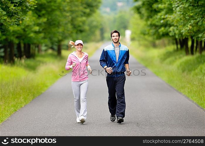 Jogging young fit couple running park road in sportswear tracksuit