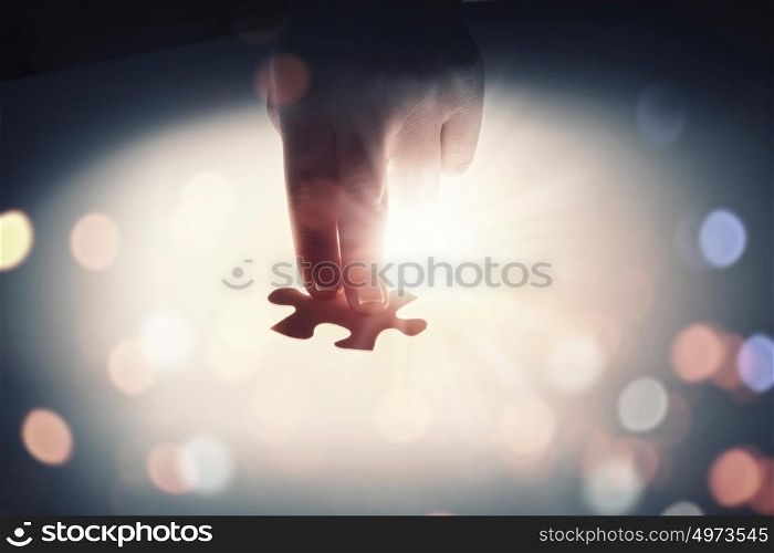 Join together. Hand connecting two jigsaw glowing puzzle pieces