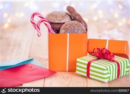 Jolly image with wrapped gifts, colorful envelopes, on a wooden table with Christmas bokeh lights in the background.