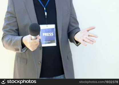 Journalist holding microphone, gesturing during media interview