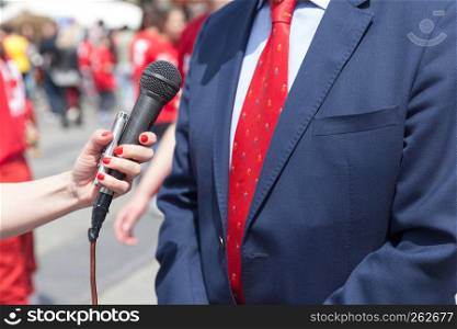 Journalist holding microphone making media interview with business person or politician
