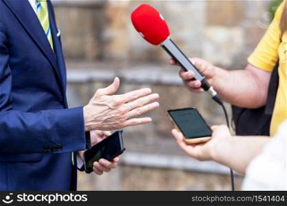 Journalist holding microphone making media interview with politician or business person