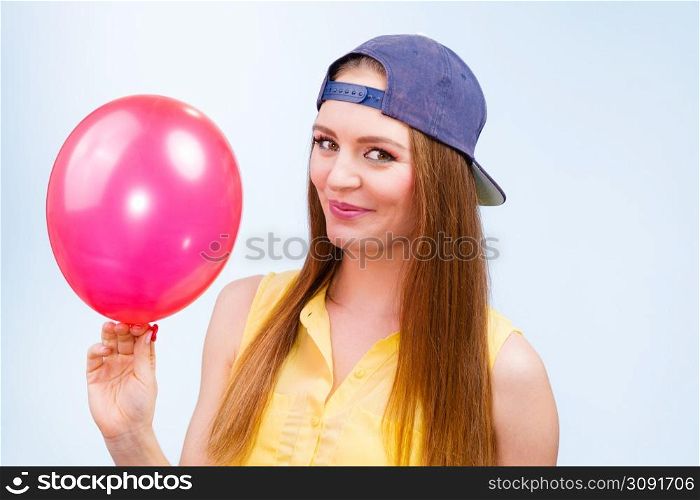Joy and fun. Beauty smiling teenage girl with red pink balloon. Young charming trendy woman in fashion clothes against blue background. . Happy teenage girl with red balloon.