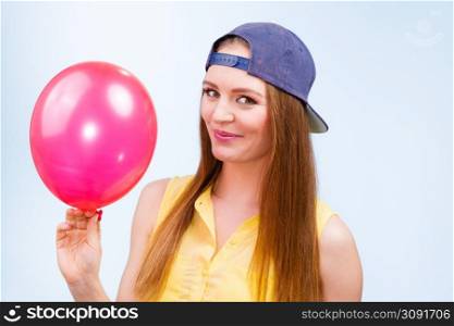 Joy and fun. Beauty smiling teenage girl with red pink balloon. Young charming trendy woman in fashion clothes against blue background. . Happy teenage girl with red balloon.