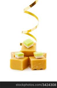 Joy of food - caramel fudge with golden ribbon. Isolated on white background. . Caramel fudge with golden ribbon