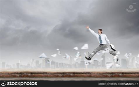 Joy of success. Young successful businessman jumping against city background