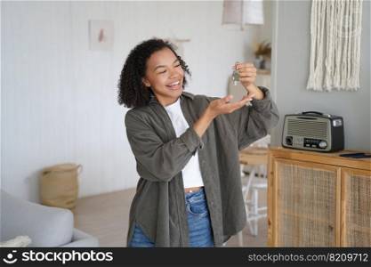 Joyful biracial teen girl tenant homeowner shows home keys to new first house. Happy young lady holding key to apartment, celebrates moving to own housing. Real estate sale, separation from parents.. Joyful biracial teen girl tenant homeowner shows home keys to new first house, celebrates relocation