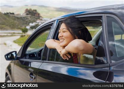 joyful chinese young female looking nature from car window
