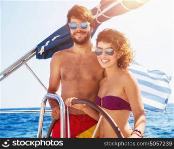 Joyful couple driving sailboat, enjoying water summer adventure, spending honeymoon in the sea cruise, romantic relationship, happy young family
