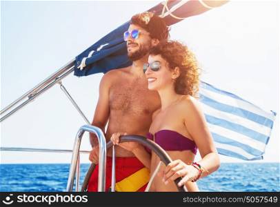 Joyful couple driving sailboat, enjoying water summer adventure, spending honeymoon in the sea cruise, romantic relationship, happy young family