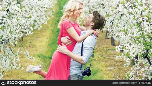 Joyful couple in the fragrant apple orchard