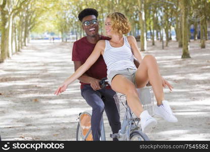 joyful couple riding one bike in public park