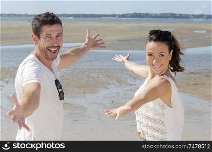 joyful couple with open arms on the sea