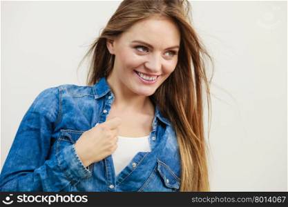 Joyful fashionable woman in denim shirt. Freedom and joy. Young attractive happy girl enjoy her life. Smiling positive woman wearing stylish jeans clothes with blowing long hair.