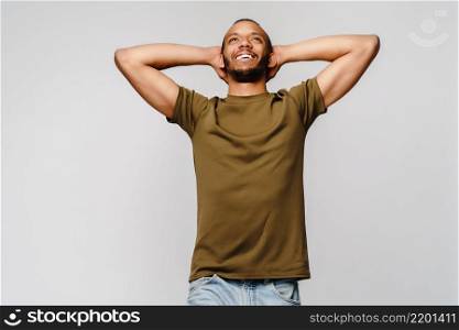 Joyful friendly african-american young man in green t-shirt over light grey background with copy space.. Joyful friendly african-american young man in green t-shirt over light grey background with copy space