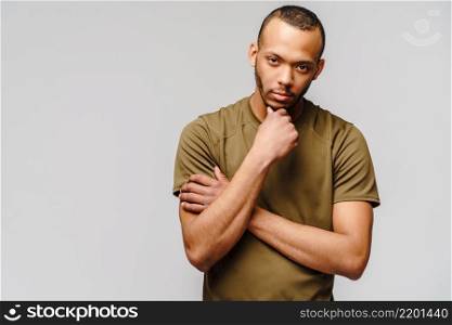 Joyful friendly african-american young man in green t-shirt over light grey background with copy space.. Joyful friendly african-american young man in green t-shirt over light grey background with copy space