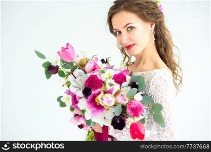 joyful girl bride in a white knitted dress posing with a bouquet of flowers in the studio on a white background