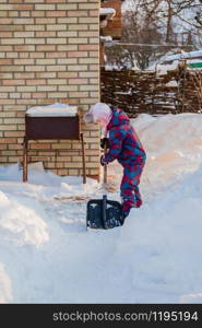 Joyful girl digs snow with a shovel, building a snow tunnel. Winter outdoor games.. Joyful girl digs snow with a shovel, building a snow tunnel