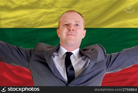 joyful investor spreading arms after good business investment in lithuania, in front of flag