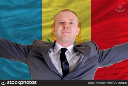 joyful investor spreading arms after good business investment in moldova, in front of flag
