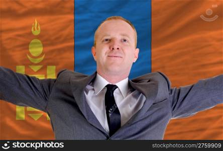 joyful investor spreading arms after good business investment in mongolia, in front of flag