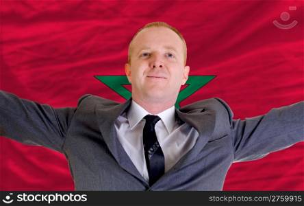 joyful investor spreading arms after good business investment in morroco, in front of flag