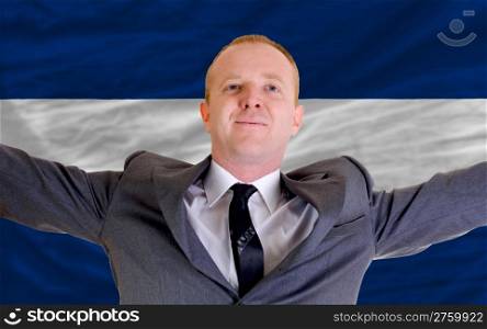 joyful investor spreading arms after good business investment in nicaragua, in front of flag