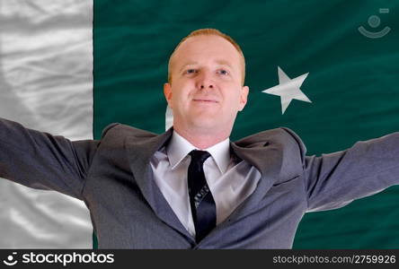 joyful investor spreading arms after good business investment in pakistan, in front of flag