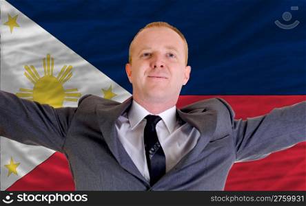 joyful investor spreading arms after good business investment in phillipines, in front of flag