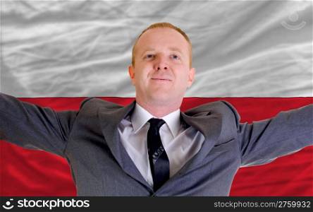 joyful investor spreading arms after good business investment in poland, in front of flag