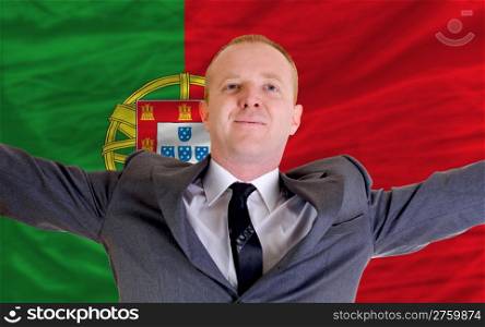 joyful investor spreading arms after good business investment in portugal, in front of flag