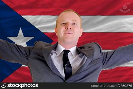 joyful investor spreading arms after good business investment in puertorico, in front of flag