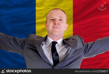 joyful investor spreading arms after good business investment in romania, in front of flag
