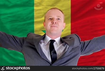 joyful investor spreading arms after good business investment in senegal, in front of flag