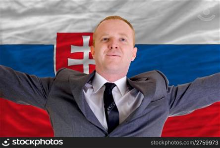 joyful investor spreading arms after good business investment in slovakia, in front of flag