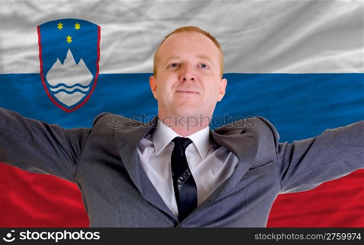 joyful investor spreading arms after good business investment in slovenia, in front of flag
