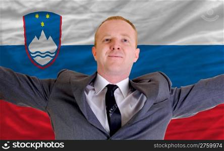 joyful investor spreading arms after good business investment in slovenia, in front of flag