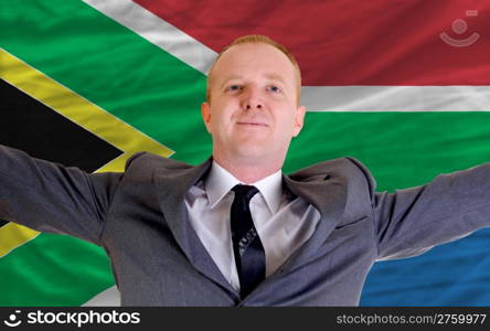 joyful investor spreading arms after good business investment in south africa, in front of flag