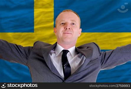 joyful investor spreading arms after good business investment in sweden, in front of flag