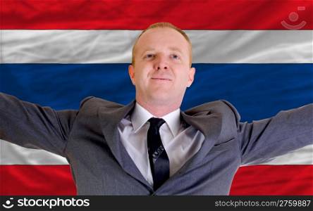 joyful investor spreading arms after good business investment in thailand, in front of flag