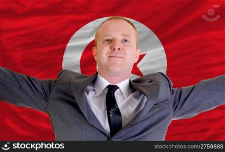 joyful investor spreading arms after good business investment in tunisia, in front of flag
