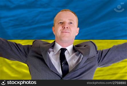 joyful investor spreading arms after good business investment in ukraine, in front of flag