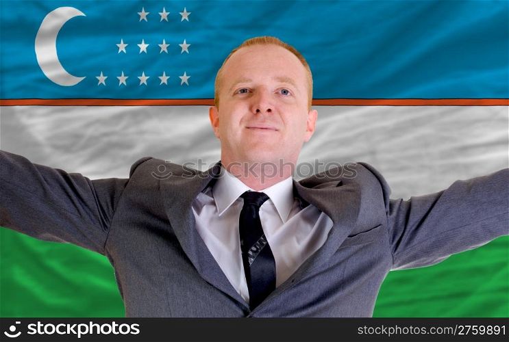 joyful investor spreading arms after good business investment in uzbekistan, in front of flag