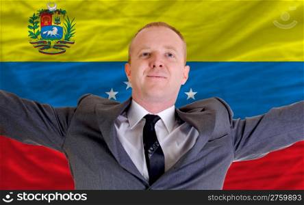 joyful investor spreading arms after good business investment in venezuela, in front of flag