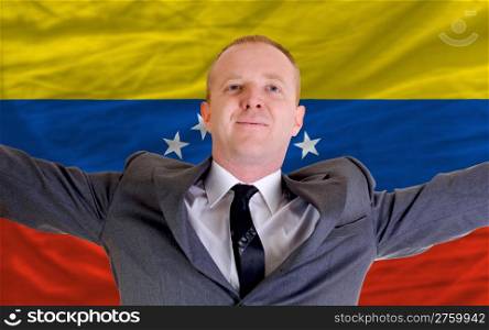 joyful investor spreading arms after good business investment in venezuela, in front of flag