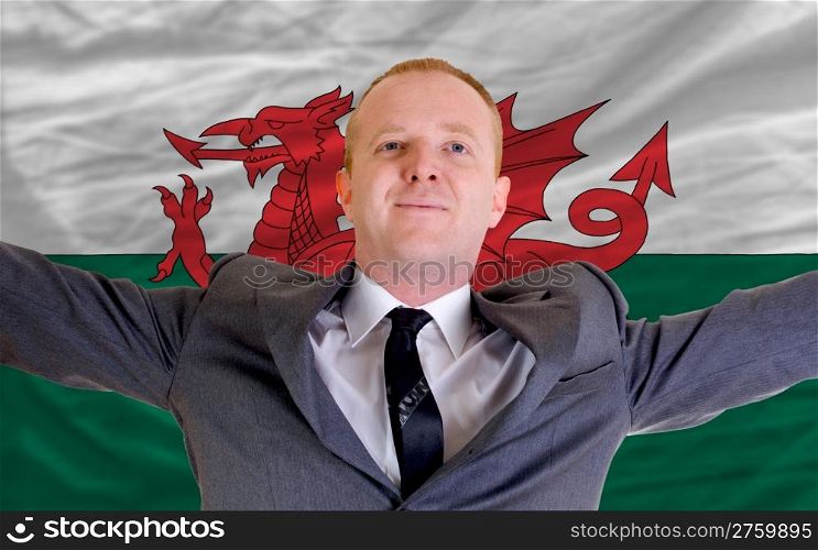 joyful investor spreading arms after good business investment in wales, in front of flag